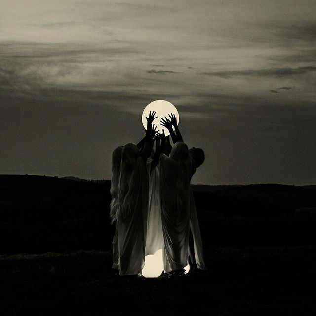 halloween samhain aesthetic photo of group of witchy women holding the moon