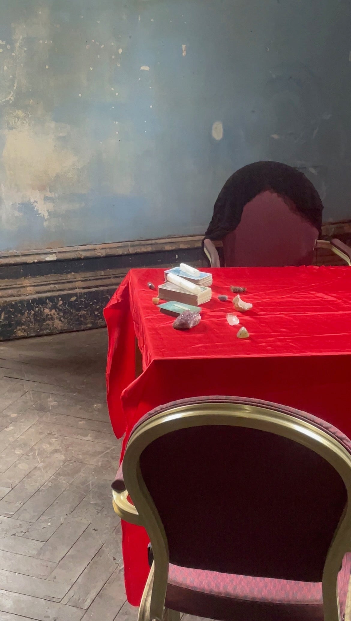 tarot cards and healing crystals on red tablecloth in gothic haunted mansion setting